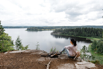 Girl tourist sits on a mountain overlooking the lake