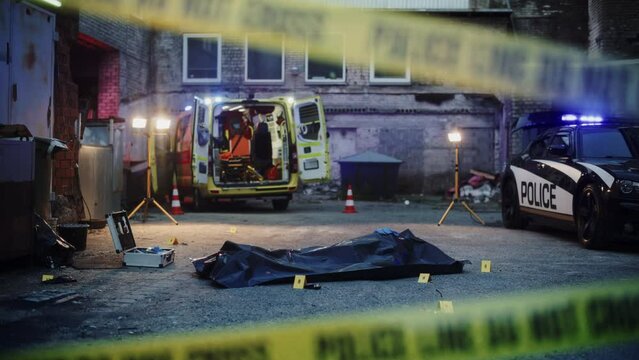 Night Establishing Shot: Empty Crime Scene in Back Alley. Covered Victim's Body on the Floor with Marked Evidence. Paramedics, Police and Forensics are on Site. Do-not-Cross Tape Restricting the Area