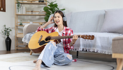 Asian female artist playing the guitar and singing happily in the living room, Relaxation with music therapy, Spending free time with music, Joy of playing music, Acoustic guitar.