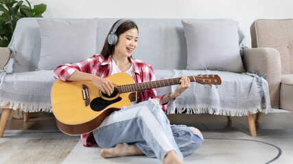 Asian female artist playing the guitar and singing happily in the living room, Relaxation with...
