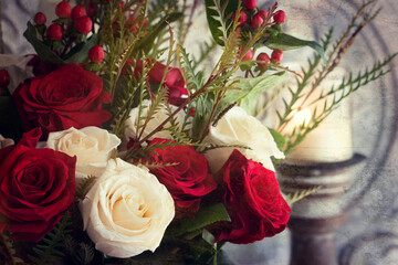 Christmas roses, red and white with candle in background