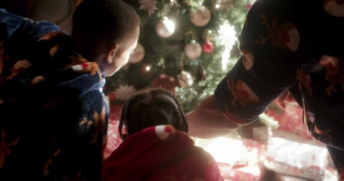 Father with sons at Christmas tree in living room