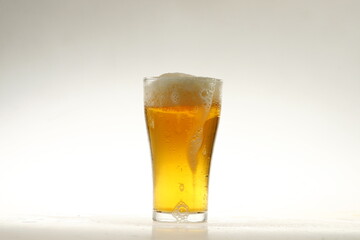 Foaming mug of beer in a glass against a white background