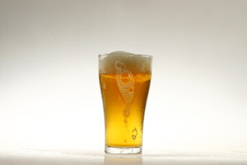 Foaming mug of beer in a glass against a white background