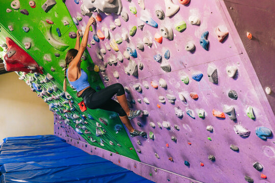 Female climber hanging on tilted wall