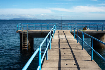 Obraz premium Resting man sunbathing on the pier. Looks at the ocean.