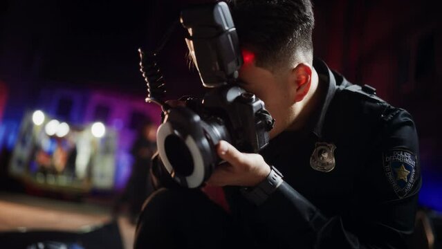 Close Up Shot: Asian Male Police Officer Taking Photos on a Crime Scene at Night. Professional Young Policeman Doing Fieldwork, Working on a Case, Photographing Evidence and Clues Left by the Criminal