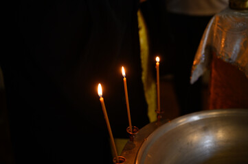Burning church candles in a gilded candlestick in a temple in the dark