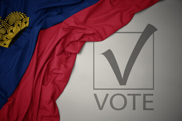 waving colorful national flag of liechtenstein on a gray background with text vote. 3D illustration