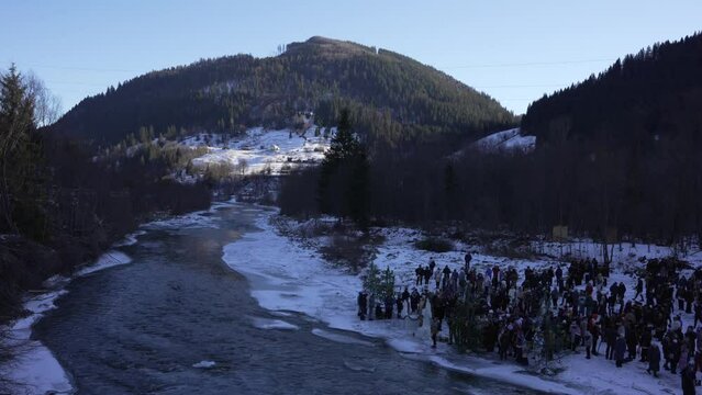People celebrate baptism of a Christ in mountains on river of ice.