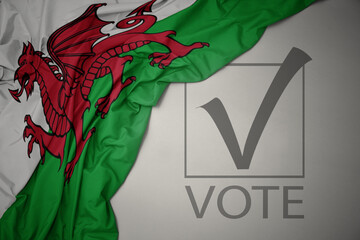 waving colorful national flag of wales on a gray background with text vote. 3D illustration