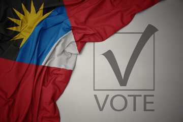 waving colorful national flag of antigua and barbuda on a gray background with text vote. 3D illustration