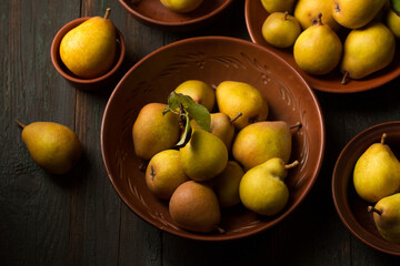 Ripe pears in ceramic bowls on a dark background