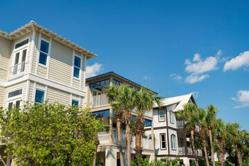Fototapeta na wymiar Plants and palm trees at the front of houses with balconies under the blue sky at Destin, Florida