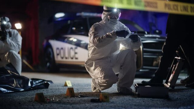 Crime Scene Investigation Team Working on a New Murder Case. Forensics Expert Using Equipment to Properly Package a Bloodied Knife in a Plastic Bag. Shocking Case of Street Violence Incident