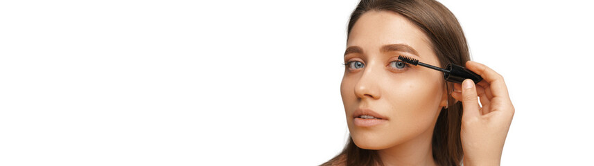 Close up banner photo with copy space of a young blonde woman using mascara.