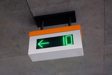 White and orange parking space availability sign hanging from concrete parking structure ceiling