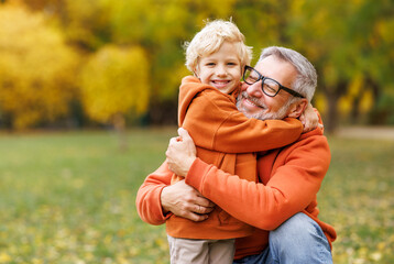 happy   grandfather and grandson hug on autumn walk in park
