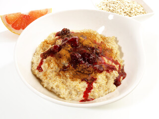 Porridge in a white Bowl; Oatmeal with Berries and Cinnamon isolated on white Background