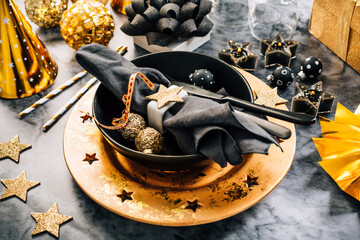 Glamorous black and gold place setting with modern plates for New Years Eve and Christmas