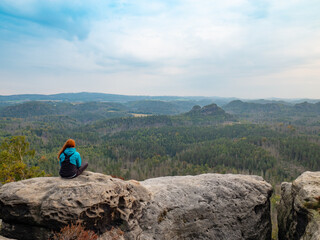 Peaceful landscape. pretty girl sitting on the rocks, looking far away - 550635837