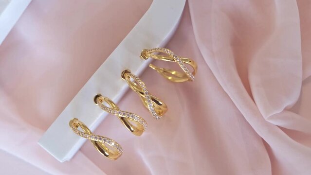 Hoop Earrings on white stand sitting on folded pink cloth