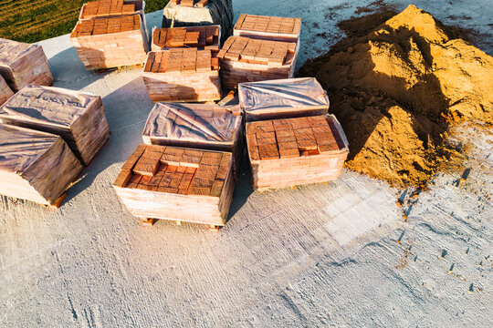 Pallets with red ceramic bricks on the roof of a building under construction. Preparatory work for laying bricks. Top view of the construction site.