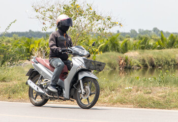 Obraz na płótnie Canvas A man with helmet rides a motorcycle on a rural road