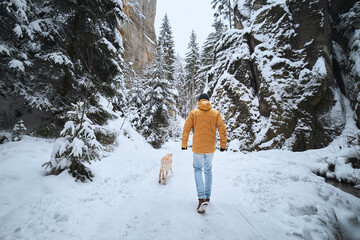 Man with dog during winter day. Pet owner walking on snowy footway with his labrador retriever. .