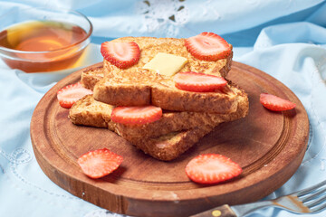 Slices of bread, French Toast garnished with strawberries, on morning scene.
