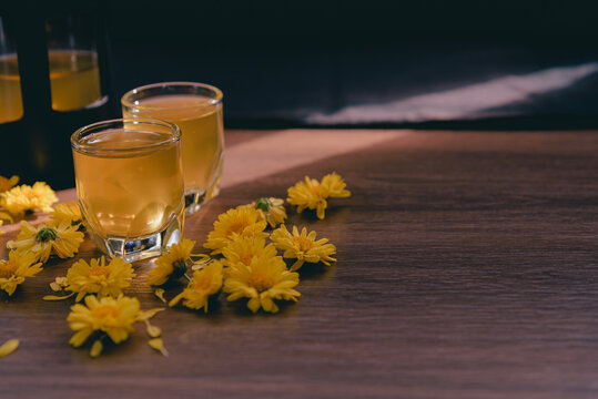 Chrysanthemum tea in glass on wooden table and flowers with sun light and black background,Healthy beverage,juice for drink,Help reduce blood pressure,prevent heart disease, Herbs and medical concept.