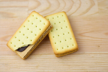 Pile of cracker sandwiches with chocolate and cheese filling on wooden background