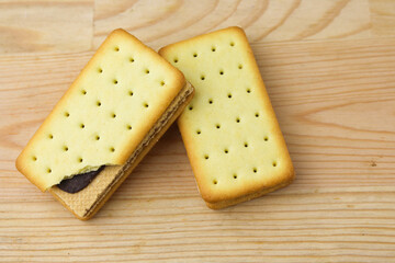 Pile of cracker sandwiches with chocolate and cheese filling on wooden background