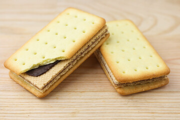 Pile of cracker sandwiches with chocolate and cheese filling on wooden background