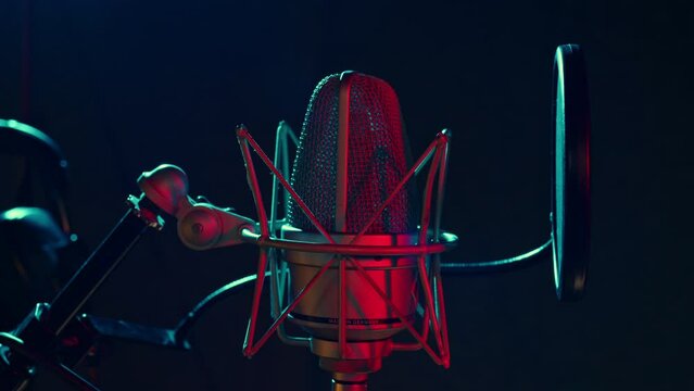 Professional microphone is in dark recording hall. Sound department with musical equipment. Audio studio for radio broadcast, production of hit songs, phonogram, singer albums. Close up