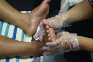 A foot massage is being performed by a male masseur