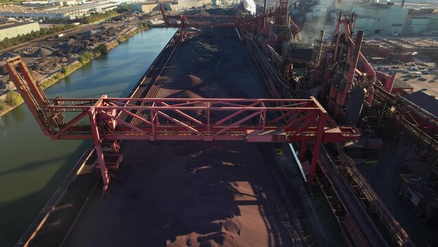 Urban area of steel factory manufacturing during sunset golden hour. Metallurgical plant with big storage of iron ore, compound of iron, and other minerals to make high quality flat carbon steel.