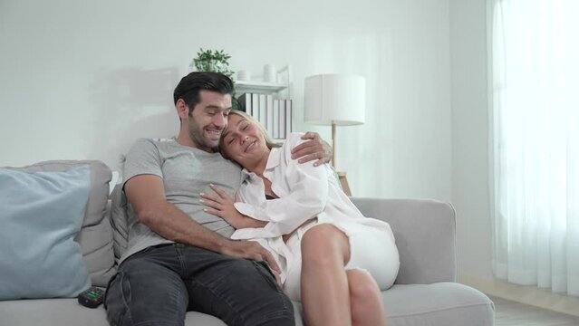 Young caucasian couple relaxing together on sofa in living room at home.