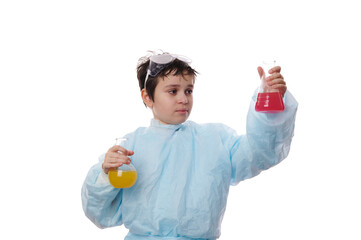 Smart chemist schoolboy wearing labcoat and goggles, conducts scientific experiments at chemistry class, watches a chemical reaction taking place in a flat-bottomed flask, isolated on white background