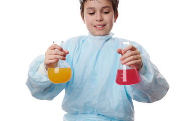 Selective focus on laboratory glassware with colored chemicals, in the hands of a schoolboy, in a...