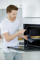 man cooking at home burns fingers on oven