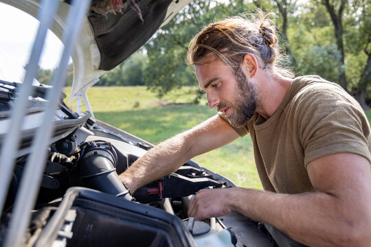 Man working outdoors on the engine compartment of a van