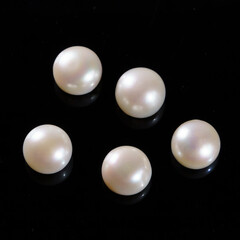 Natural pearls on a black background. White, yellowish round pearls