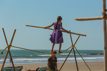 Girl acrobat on the beach along the coast of Goa in India