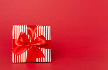 Gift box with red ribbon bow on color background
