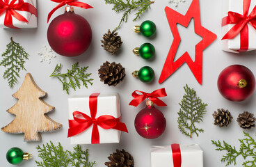 Flat lay with christmas gift boxes, toys, juniper and cones on color background