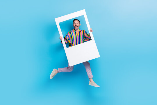 Full length photo of bearded cheerful crazy funky man wear trendy striped clothes hold big photography isolated on blue color background