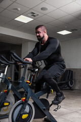 Fototapeta na wymiar Working out on the exercise bicycle in the gym