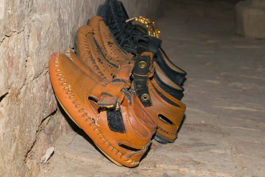 Close up image of a set of shoes of different colors placed beside a wall with blurred background and selective focus. Macro image of shoes near a wall.