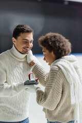 Excited african american woman touching boyfriend with proposal ring on ice rink